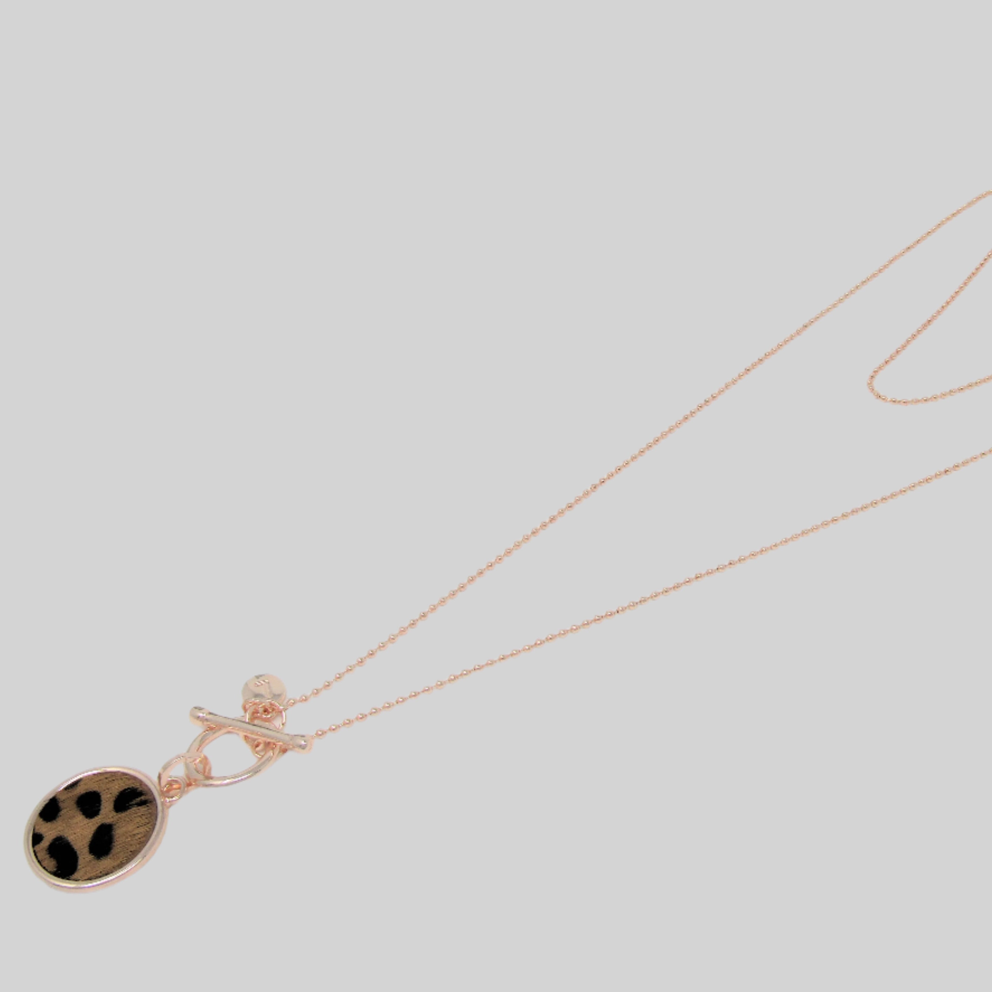 A rose gold-colored necklace with a brown leopard print pendant,