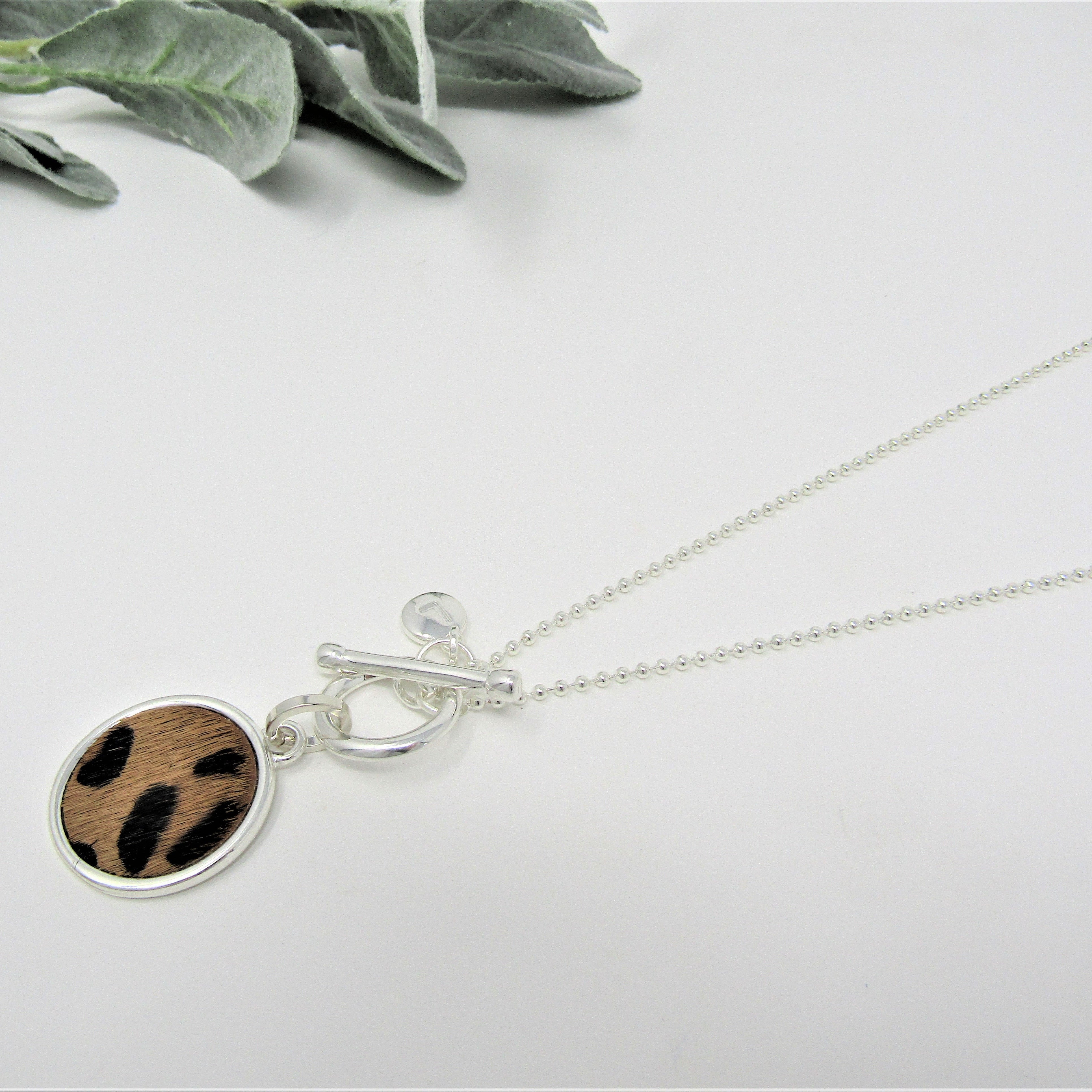 Necklace with a round pendant featuring a fabric-like pattern on a light gray background.