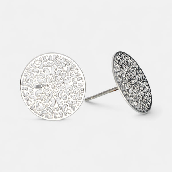 Silver round earrings with intricate designs on a light gray background